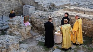 Priests conduct a religious ceremony at historical stone ruins outdoors.
